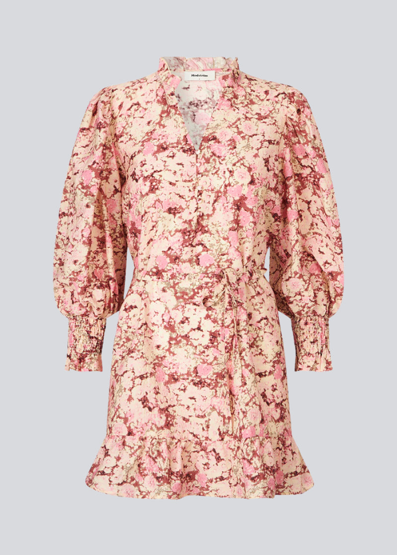 Kort langærmet kjole med v-hals og bindebånd i taljen. MeliaMD print LS dress har en smock detalje ved ærmerne og en flæsekant. Kjolen har et smukt blomstret print i lyserøde nuancer. Modellen er 177 cm og har en str. S/36 på.