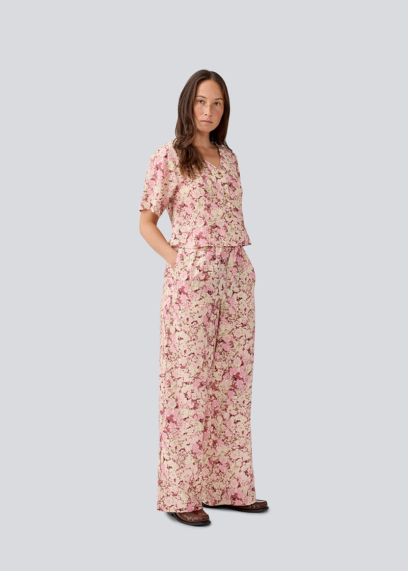 Figursyet top med korte ærmer. MeliaMD print top har en v-hals og knappelukning fortil. Modellen er 177 cm og har en str S/36 på.
