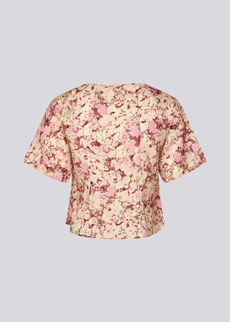 Figursyet top med korte ærmer. MeliaMD print top har en v-hals og knappelukning fortil. Modellen er 177 cm og har en str S/36 på.