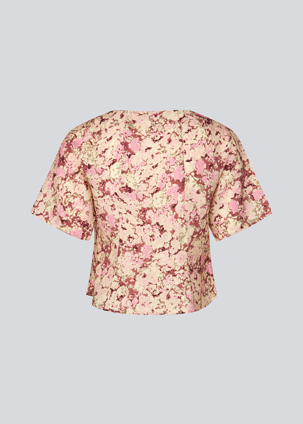 Figursyet top med korte ærmer. MeliaMD print top har en v-hals og knappelukning fortil. Modellen er 177 cm og har en str S/36 på.