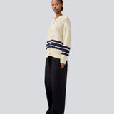 Løs strikket cardigan i beige med mørkeblå striber i kabel strik. MetteMD cardigan er let gennemsigtig, har løse ærmer og en knappelukning fortil. Modellen er 177 cm og har en str. S/36 på.
