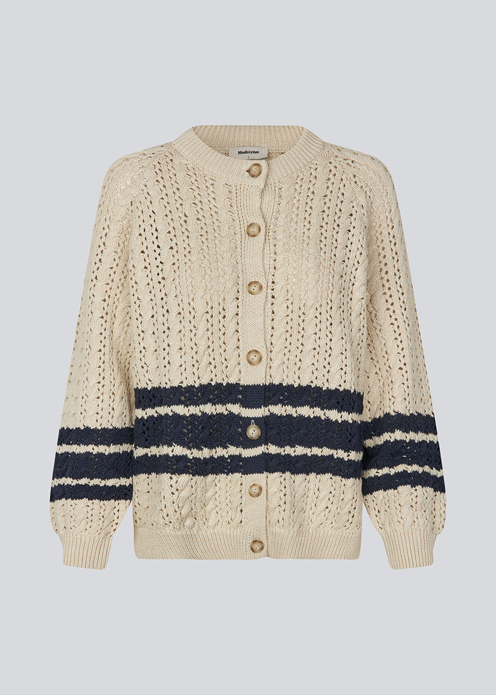 Løs strikket cardigan i beige med mørkeblå striber i kabel strik. MetteMD cardigan er let gennemsigtig, har løse ærmer og en knappelukning fortil. Modellen er 177 cm og har en str. S/36 på.