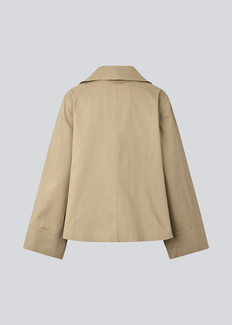 Jakke i beige med asymmetrisk lukning. MillaMD jacket har to lommer fortil, krave og brede ærmer