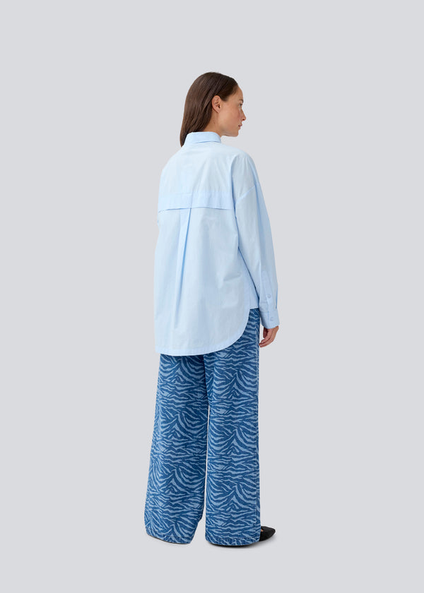 Blå klassisk skjorte med en oversize pasform. MyraMD shirt har en skjult knappelukning fortil og en slids i siden. Modellen er 177 cm og har en str. S/36 på.
