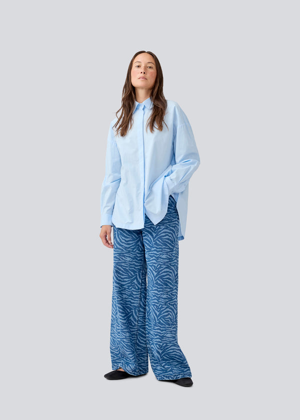 Blå klassisk skjorte med en oversize pasform. MyraMD shirt har en skjult knappelukning fortil og en slids i siden. Modellen er 177 cm og har en str. S/36 på.
