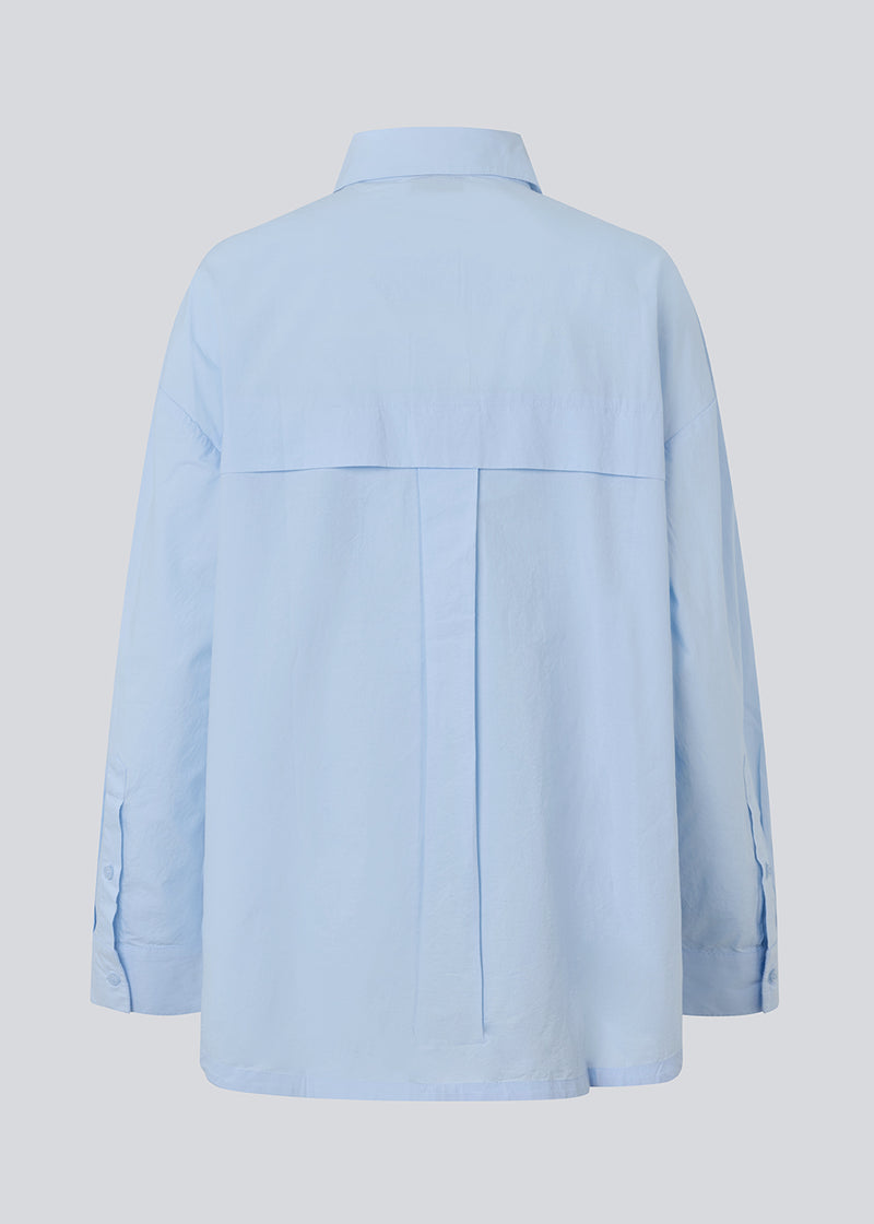 Blå klassisk skjorte med en oversize pasform. MyraMD shirt har en skjult knappelukning fortil og en slids i siden. Modellen er 177 cm og har en str. S/36 på.

