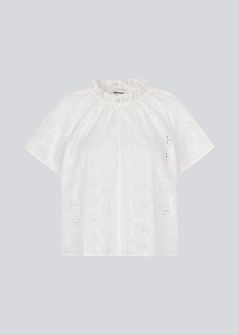 Kortærmet top i broderie anglaise. NanetteMD SS top har en løs pasform og en åbning fortil med knappelukning.