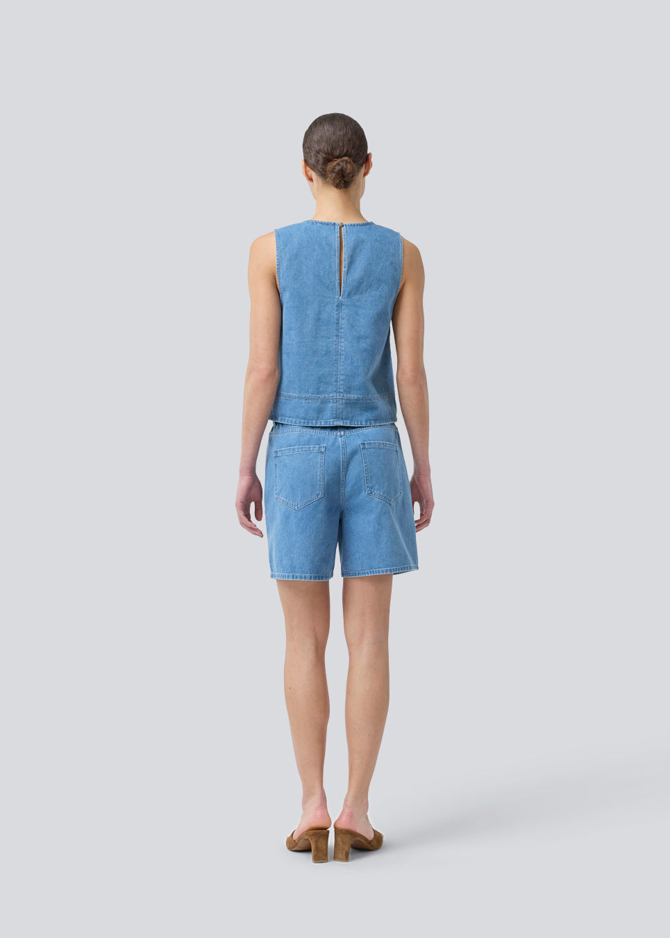Ærmeløs blå top med rund hals i bomulds denim. NaomaMD solid top har en løs pasform og en åbning i nakken med knappelukning.
