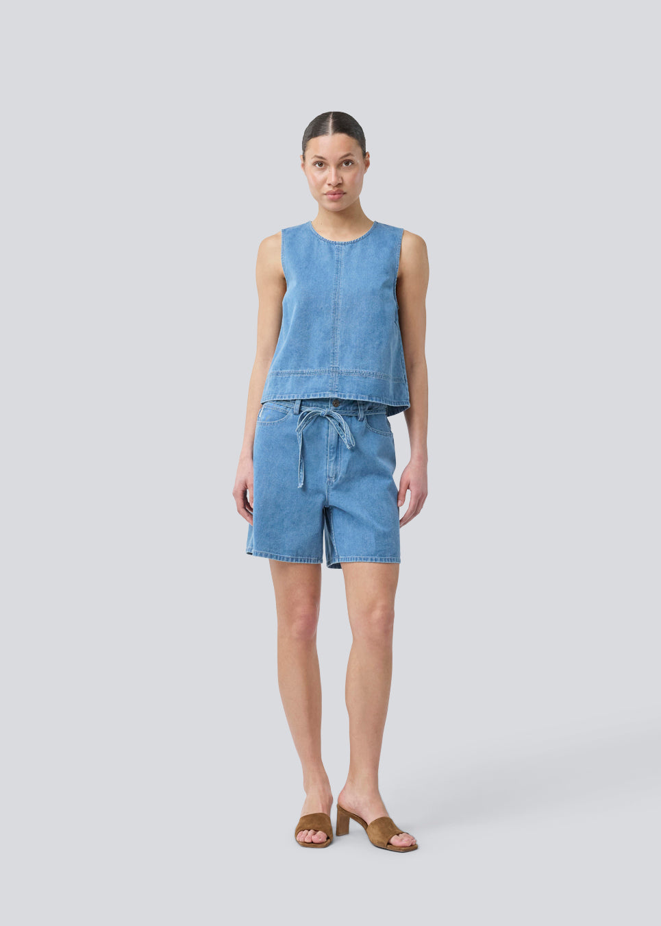 Ærmeløs blå top med rund hals i bomulds denim. NaomaMD solid top har en løs pasform og en åbning i nakken med knappelukning.
