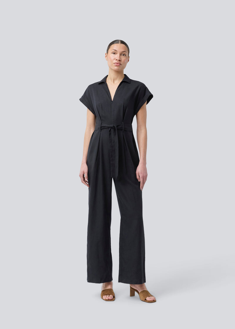Sort jumpsuit med vidde ben og bindebånd i taljen. NedraMD jumpsuit har en krave, v-hals og lynlåslukning fortil.