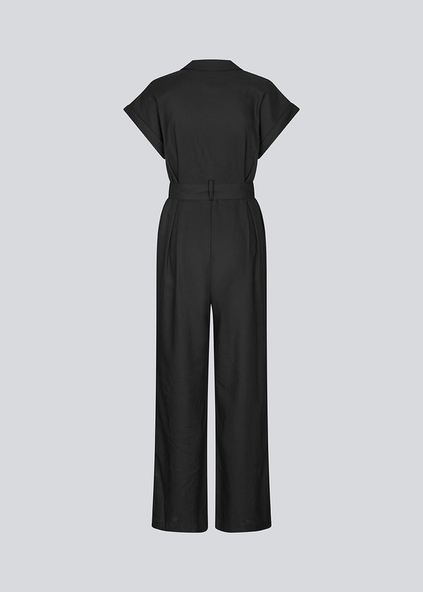 Sort jumpsuit med vidde ben og bindebånd i taljen. NedraMD jumpsuit har en krave, v-hals og lynlåslukning fortil.