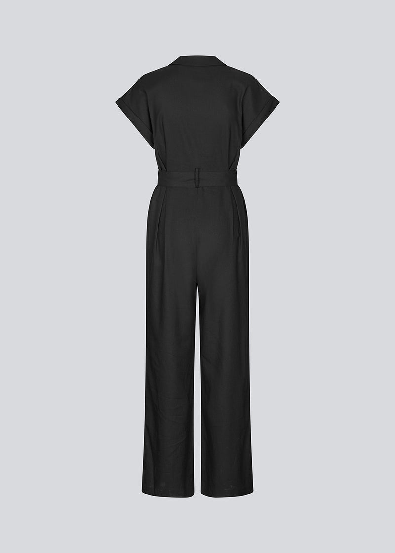 Sort jumpsuit med vidde ben og bindebånd i taljen. NedraMD jumpsuit har en krave, v-hals og lynlåslukning fortil.