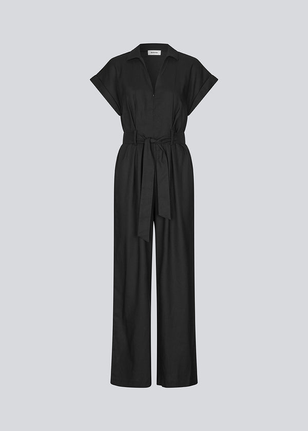 Sort jumpsuit med vidde ben og bindebånd i taljen. NedraMD jumpsuit har en krave, v-hals og lynlåslukning fortil.