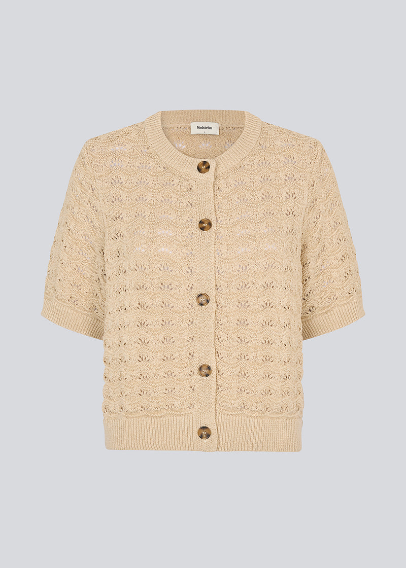Kortærmet beige cardigan i strik med pointelle mønster. NeppoMD cardigan har en løs pasform og en knappelukning fortil.