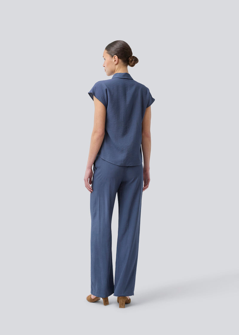 Ærmeløs skjorte i blå med knappelukning fortil i EcoVero viscose. NickiMD SS shirt har en løs pasform en rynkedetalje ved skulderen.