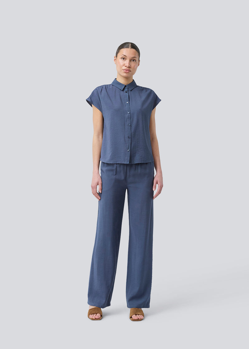 Ærmeløs skjorte i blå med knappelukning fortil i EcoVero viscose. NickiMD SS shirt har en løs pasform en rynkedetalje ved skulderen.