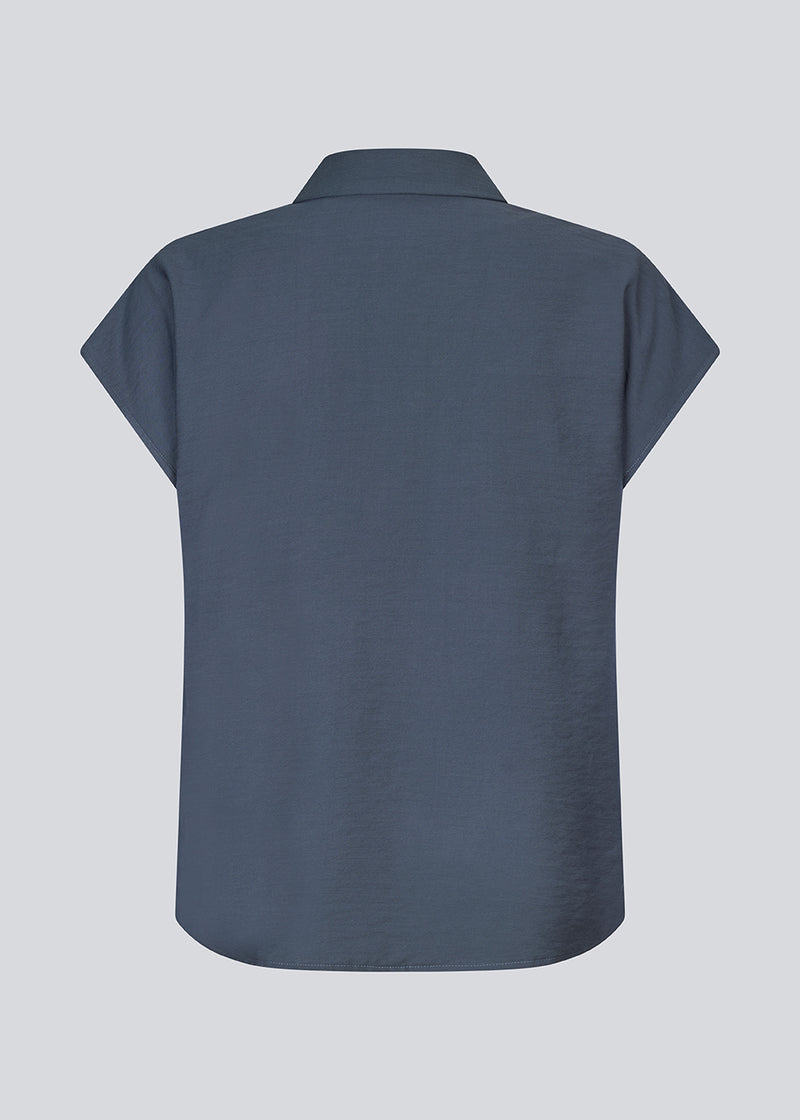 Ærmeløs skjorte i blå med knappelukning fortil i EcoVero viscose. NickiMD SS shirt har en løs pasform en rynkedetalje ved skulderen.