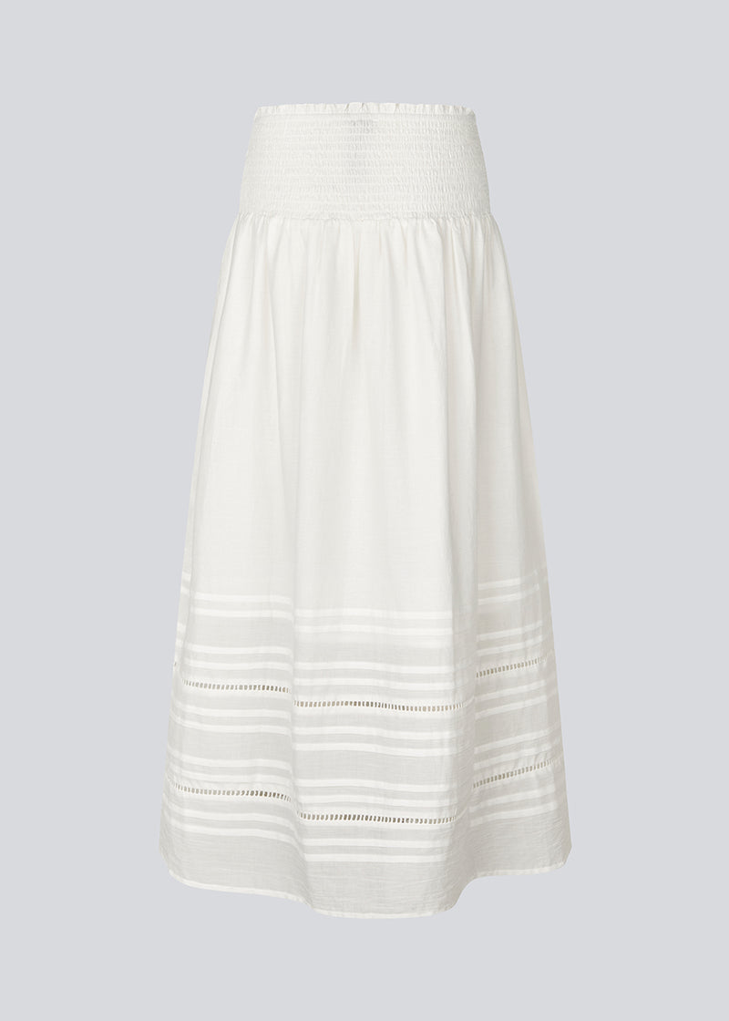 Lang nederdel i hvid i 100% økologisk bomuld. NillaMD skirt har et løst skørt med læg og flæsedetaljer og en elastisk talje med smock.