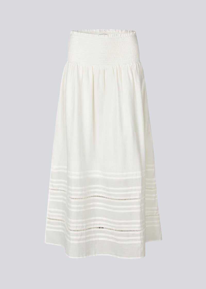 Lang nederdel i hvid i 100% økologisk bomuld. NillaMD skirt har et løst skørt med læg og flæsedetaljer og en elastisk talje med smock.