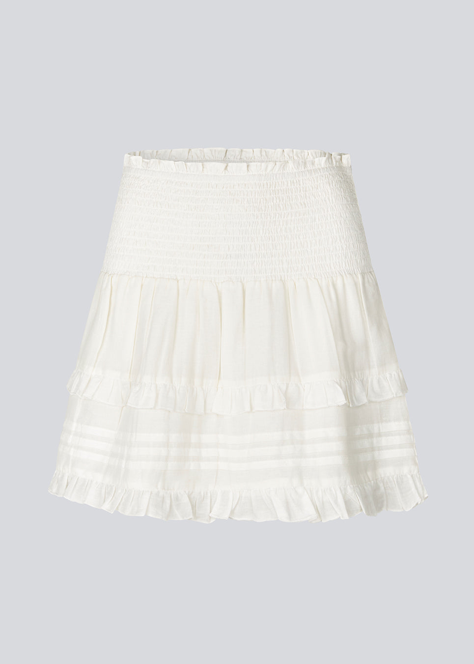 Kort hvid nederdel i 100% økologisk bomuld. NillaMD skirt har et løst skørt med læg og flæsedetaljer og en elastisk talje med smock.