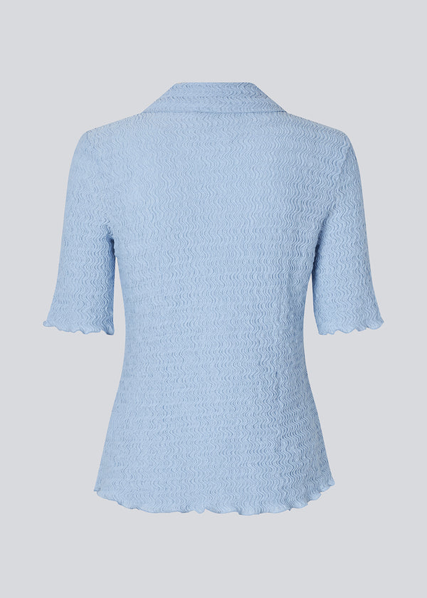 Kortærmet skjorte i lyseblå i et let og struktureret materiale. NolineMD shirt er figursyet og har en knappelukning fortil samt skjortekrave.