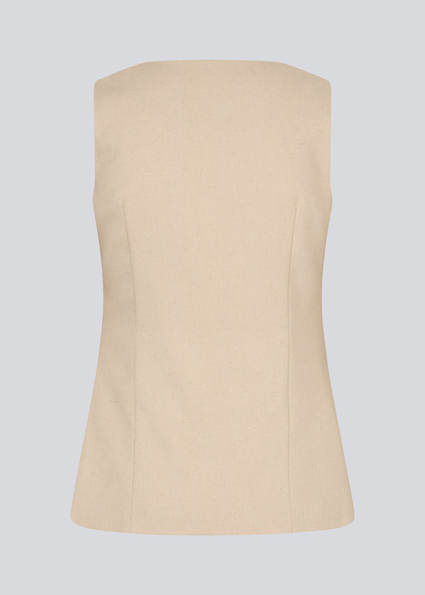 Figursyet beige vest med v-udskæring. NormaMD top har en knappelukning og to lommer fortil.
