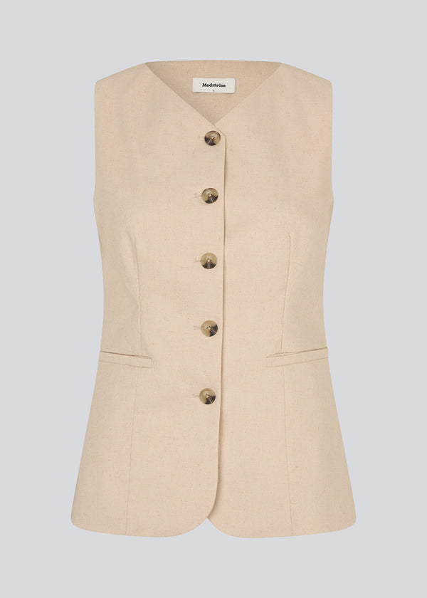 Figursyet beige vest med v-udskæring. NormaMD top har en knappelukning og to lommer fortil.
