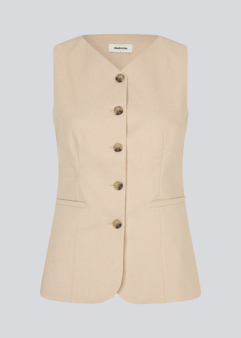 Figursyet beige vest med v-udskæring. NormaMD top har en knappelukning og to lommer fortil.
