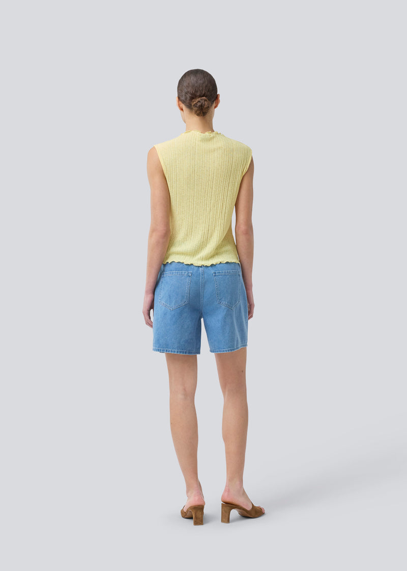 Ærmeløs top i gul i struktureret materiale med høj hals. OasisMD top har flæsesømme ved hals, ærmegab og forneden. Modellen er 175 cm og har en størrelse S/36 på.
