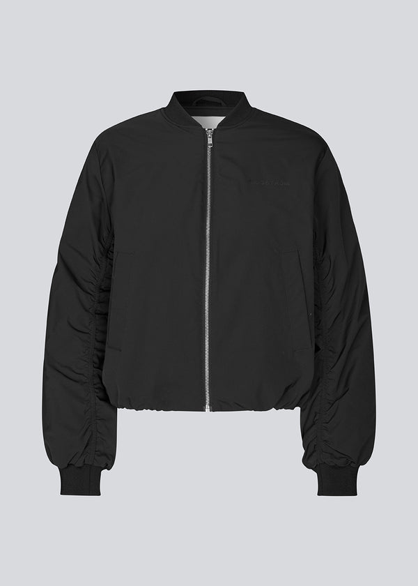 Vatteret sort bomber jacket med rynkedetalje på ærmet. Obimd jacket er let cropped og har en lynlåslukning og to forlommer.&nbsp;