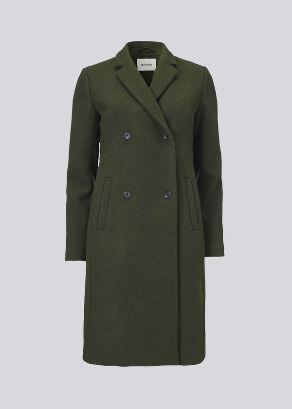 Smuk knælang uldfrakke i army grøn. Odelia coat bliver lukket fortil af fire knapper og er taljeret, hvilket giver et feminint udtryk. På grund af den høje kvalitet af uld, vil den være det oplagte valg til både efterår og de milde vintre.