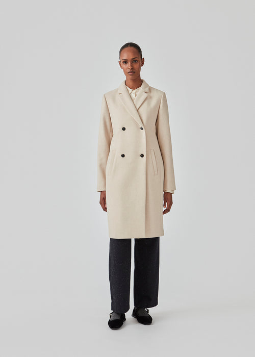 Smuk knælang uldfrakke. Odelia coat bliver lukket fortil af fire knapper og er taljeret, hvilket giver et feminint udtryk. På grund af den høje kvalitet af uld, vil den være det oplagte valg til både efterår og de 