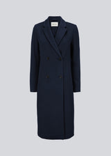 Smuk, lang uldfrakke i mørkeblå. Odelia long coat er dobbeltradet og taljeret, hvilket giver et feminint udtryk. Frakken er et oplagt valg til både efterår og de milde vintre.