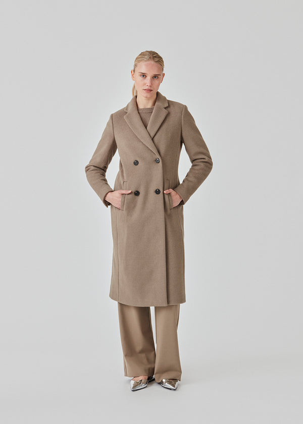 Smuk, lang uldfrakke. Odelia long coat, i Farven Spring Stone, er dobbeltradet og taljeret, hvilket giver et feminint udtryk. Frakken er et oplagt valg til både efterår og de milde vintre.