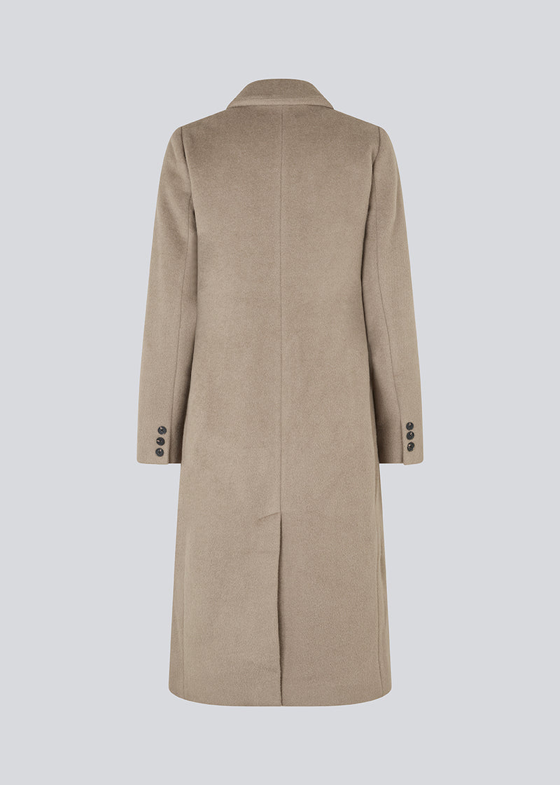 Smuk, lang uldfrakke. Odelia long coat, i Farven Spring Stone, er dobbeltradet og taljeret, hvilket giver et feminint udtryk. Frakken er et oplagt valg til både efterår og de milde vintre.