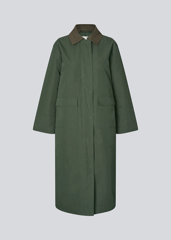 Vatteret frakke i grøn med kontrast fløjlskrave i mørkebrun. Odettemd coat har en skjult lynlåslukning, slids og to forlommer. Modellen er 175 cm og har en str. s/36 på.