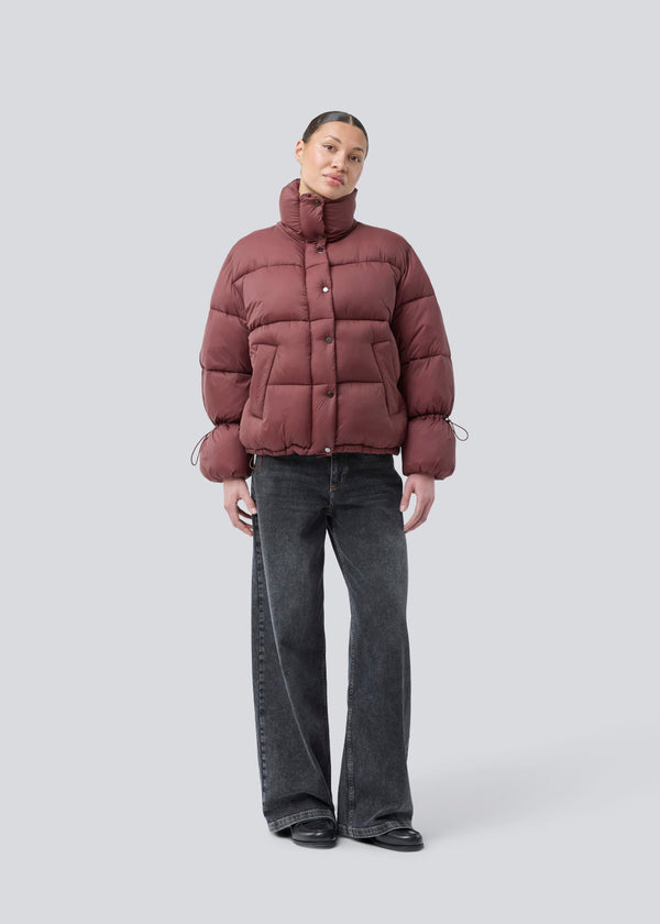Rød dunjakke med høj hals i 100% genanvendt polyester. Odinmd jacket har en lynlåslukning og en justerbar elastik i ærmet. Modellen er 175 cm og har en str. s/36 på.