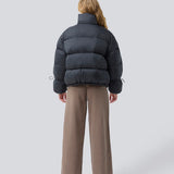 Sort dunjakke med høj hals i 100% genanvendt polyester. Odinmd jacket har en lynlåslukning og en justerbar elastik i ærmet. Modellen er 175 cm og har en str. s/36 på.
