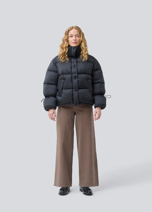 Sort dunjakke med høj hals i 100% genanvendt polyester. Odinmd jacket har en lynlåslukning og en justerbar elastik i ærmet. Modellen er 175 cm og har en str. s/36 på.
