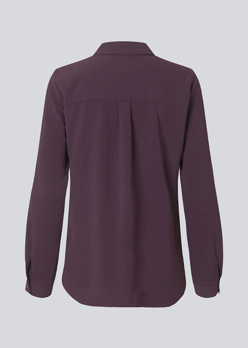 Mørklilla klassisk skjorte i en løs og afslappet pasform. Ossa shirt har en lille krave, smal manchet og knapper i matchende farve for et ensartet design. Modellen er 173 cm og har en størrelse S/36 på