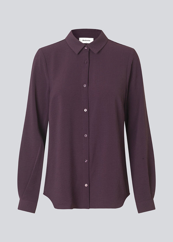 Mørklilla klassisk skjorte i en løs og afslappet pasform. Ossa shirt har en lille krave, smal manchet og knapper i matchende farve for et ensartet design. Modellen er 173 cm og har en størrelse S/36 på