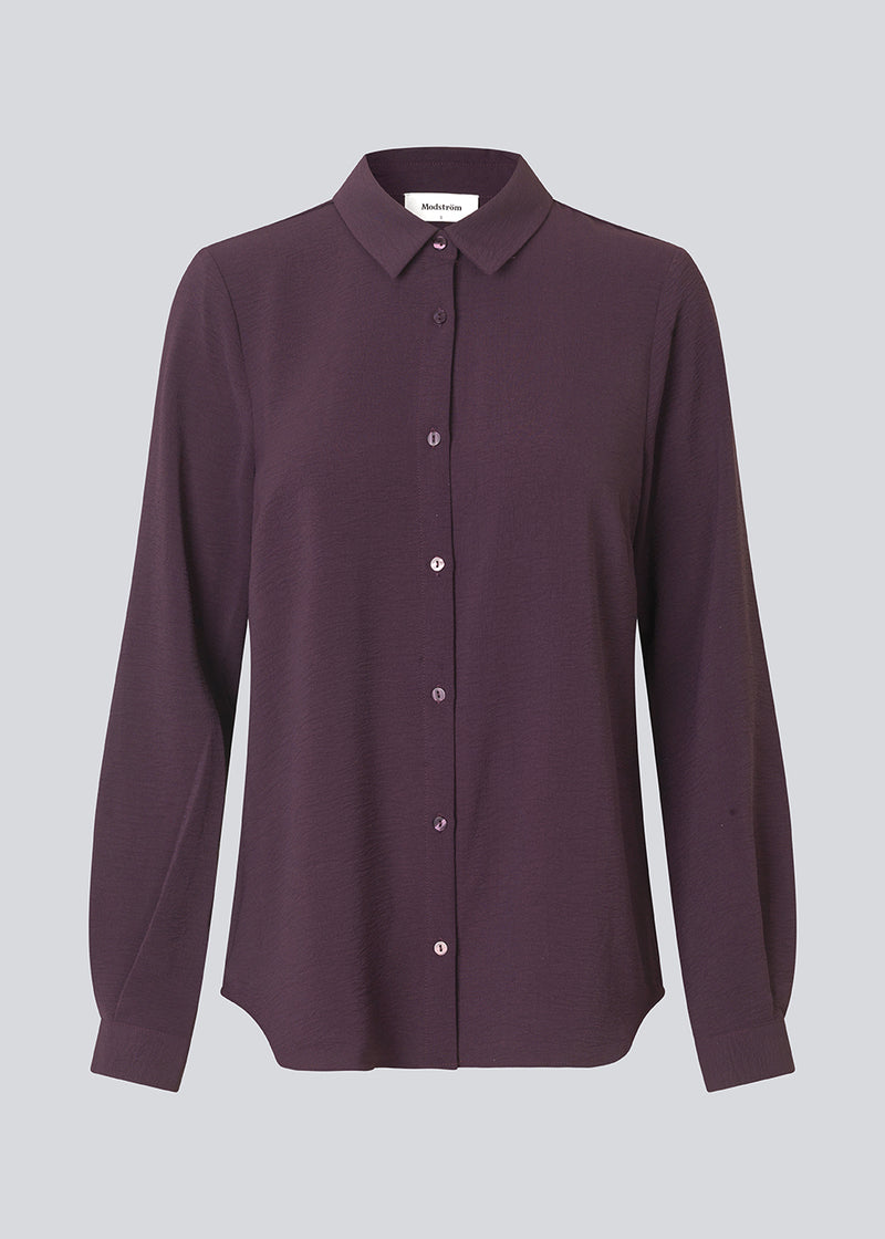 Mørklilla klassisk skjorte i en løs og afslappet pasform. Ossa shirt har en lille krave, smal manchet og knapper i matchende farve for et ensartet design. Modellen er 173 cm og har en størrelse S/36 på