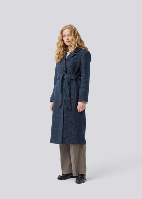 Klassisk, dobbeltradet uldfrakke i blå med krave med skjult knappelukning og bindebånd. Otillamd coat har en afslappet pasform, foer og en slids bagpå. Modellen er 175 cm og har en str. s/36 på.