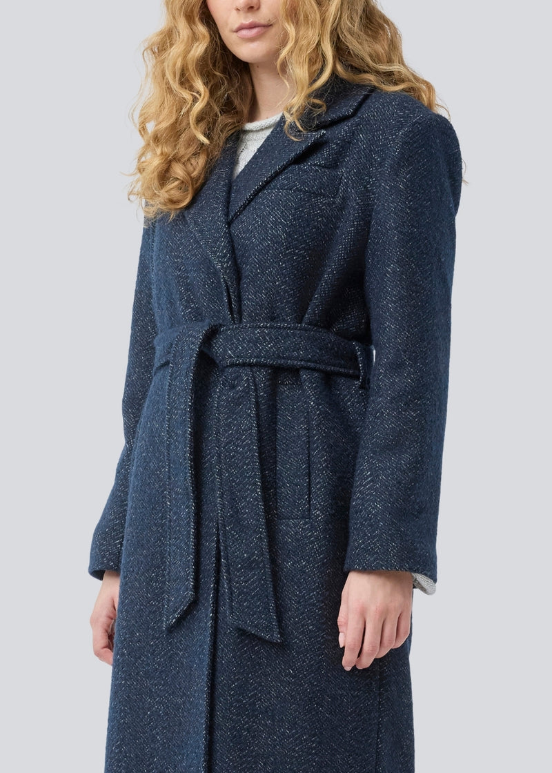 Klassisk, dobbeltradet uldfrakke i blå med krave med skjult knappelukning og bindebånd. Otillamd coat har en afslappet pasform, foer og en slids bagpå. Modellen er 175 cm og har en str. s/36 på.