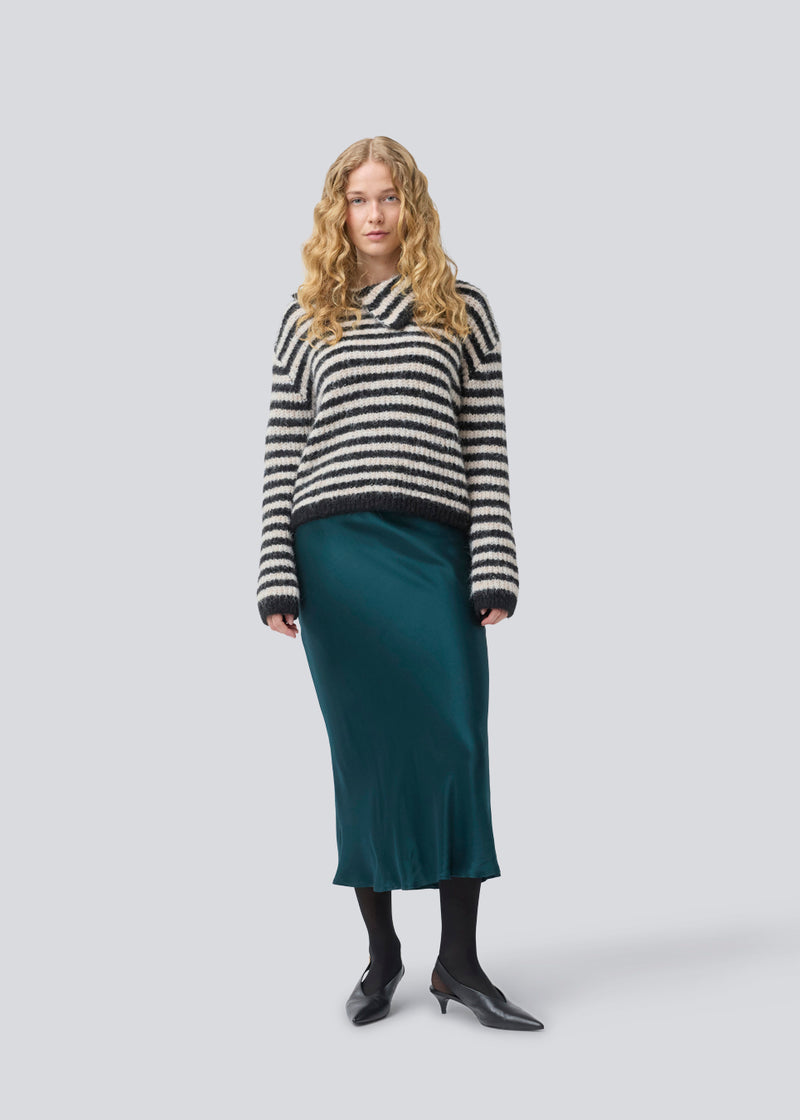 Blød strik med i genanvendt polyester. Packermd roll Neck har lange ærmer og en høj hals med slids i siden. Modellen er 175 cm og har en str. s/36 på.