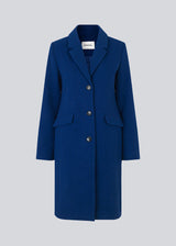 Smuk knælang uldfrakke i flot blå. Pamela coat bliver knappet fortil af 3 store knapper og er taljeret, som giver et feminint udtryk. På grund af den høje kvalitet af uld, vil den være det oplagte valg at bruge til både efterår og de milde vintre