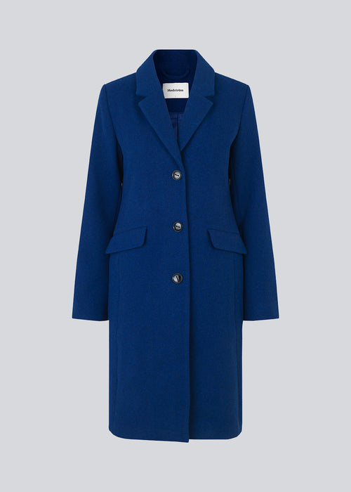 Smuk knælang uldfrakke i flot blå. Pamela coat bliver knappet fortil af 3 store knapper og er taljeret, som giver et feminint udtryk. På grund af den høje kvalitet af uld, vil den være det oplagte valg at bruge til både efterår og de milde vintre