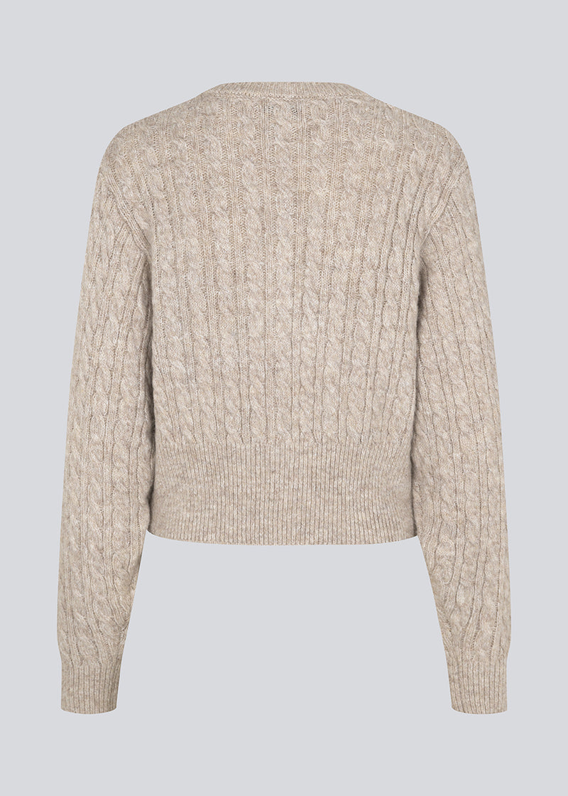 Strikket cardigan i kabelstrik med perleknapper. Pammiemd cardigan har en rund hals og ribkant.