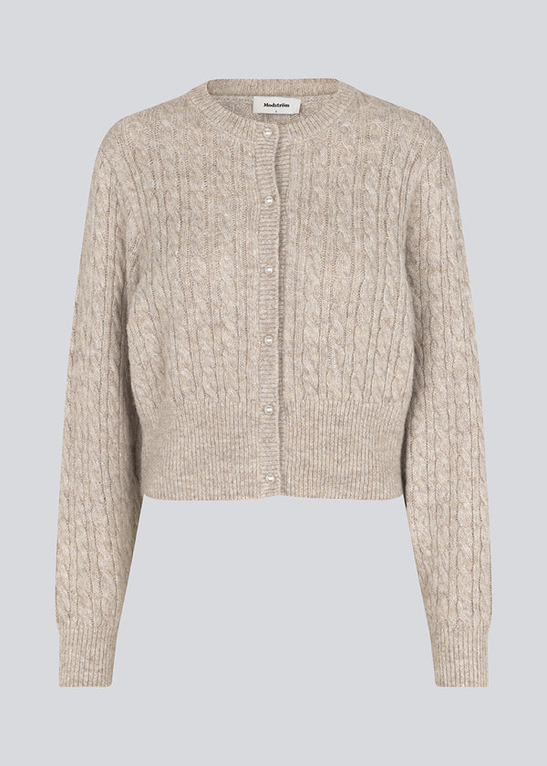 Strikket cardigan i kabelstrik med perleknapper. Pammiemd cardigan har en rund hals og ribkant.