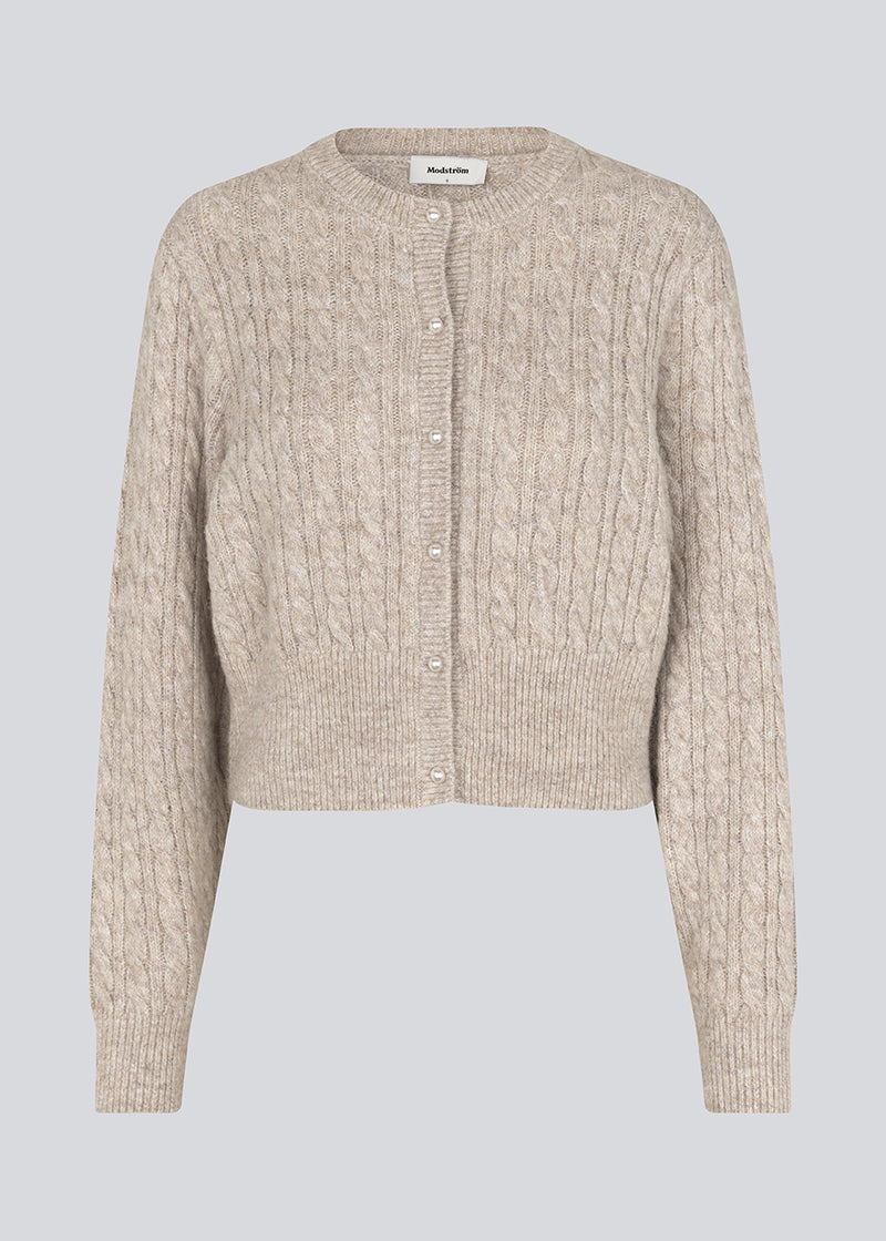 Strikket cardigan i kabelstrik med perleknapper. Pammiemd cardigan har en rund hals og ribkant.